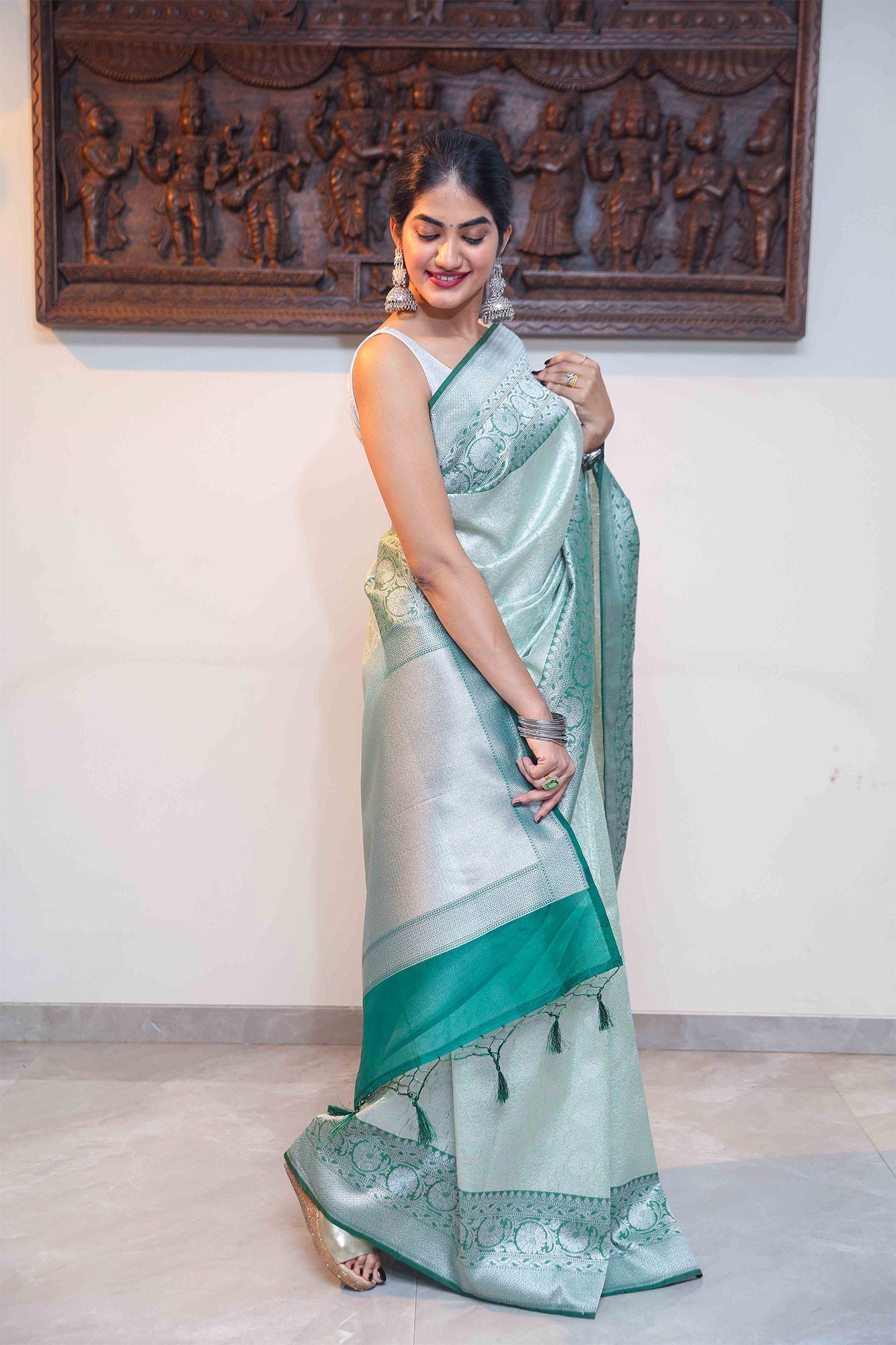 Model wearing Handloom Banarasi saree in dual green tones with subtle zari work and heavy border – traditional ethnic wear.