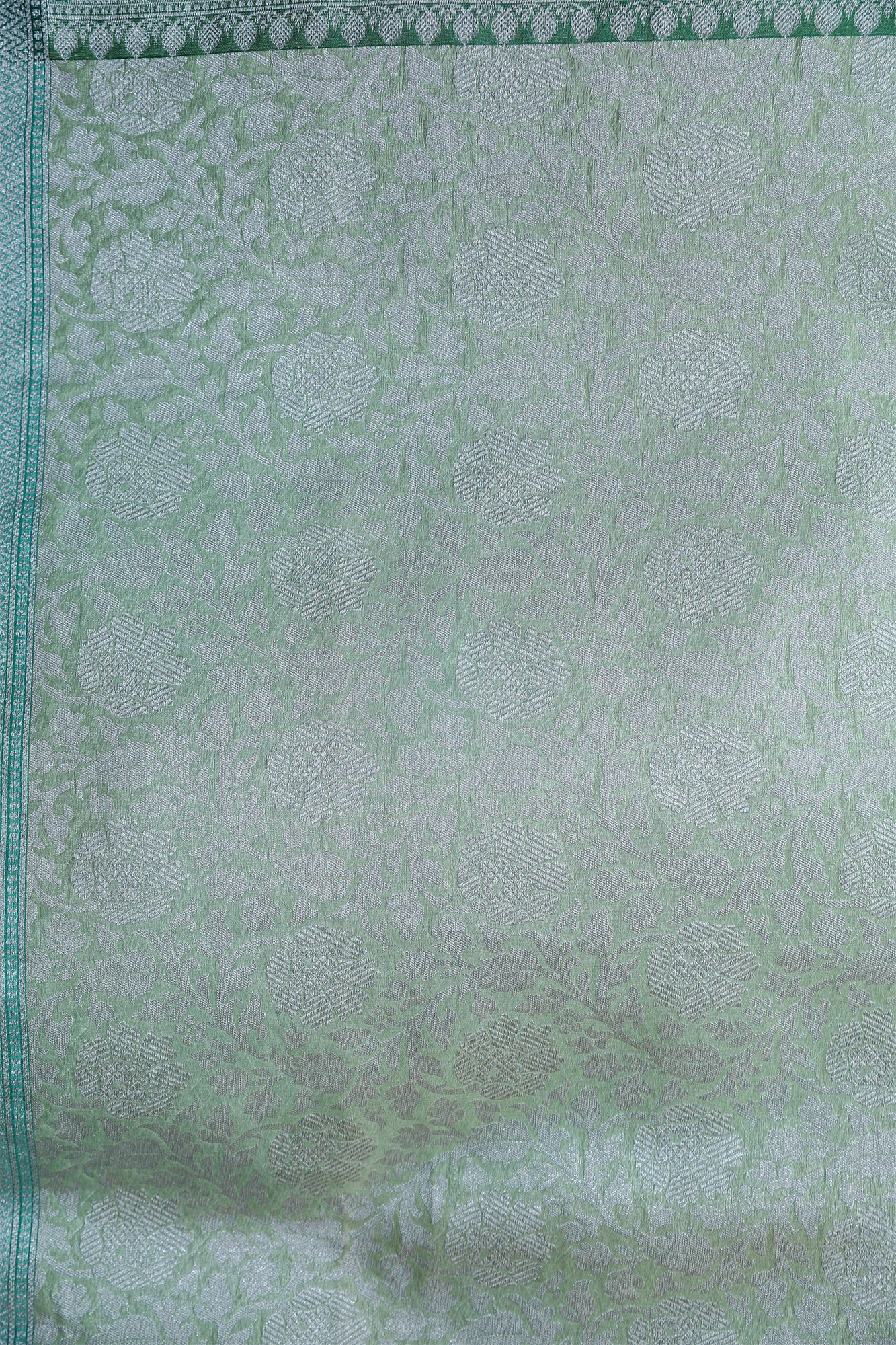 Close-up of silver zari jaal on exclusive Banarasi saree in Pashmina Kora Silk – elegant detailing for family occasions.